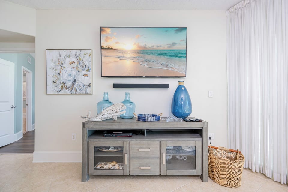 Brightly decorated living space featuring a large TV, coastal artwork, and stylish decor elements for a relaxing atmosphere