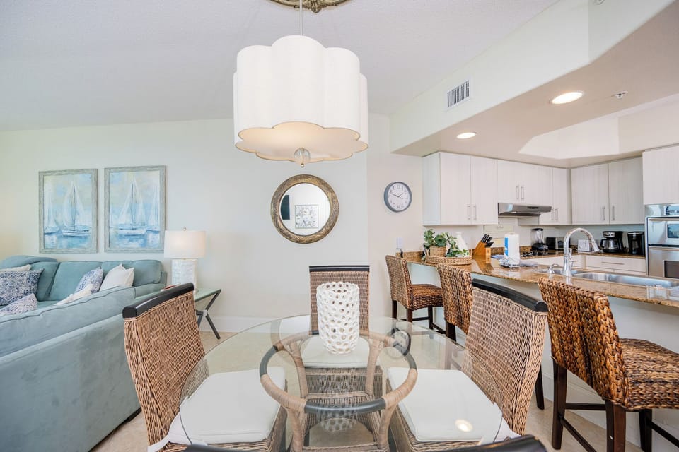 Dining area featuring coastal decor, a glass dining table, and a modern kitchen with stainless appliances
