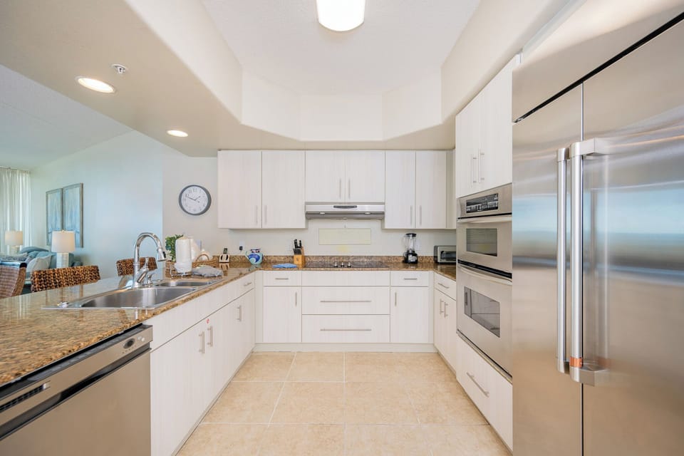 Sleek modern kitchen featuring stainless appliances, granite countertops, and a view of the inviting living area
