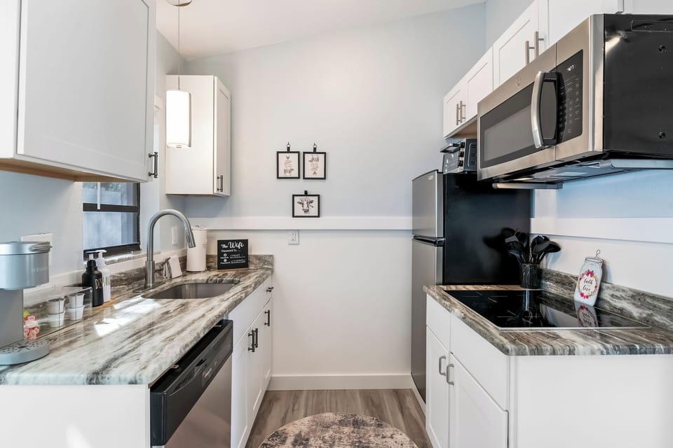 Compact kitchen with white cabinets, black appliances, and sink area.