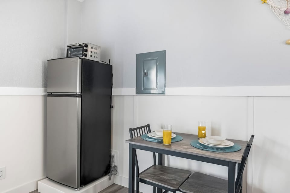 Mini dining area with fridge, table, and two drinks ready.