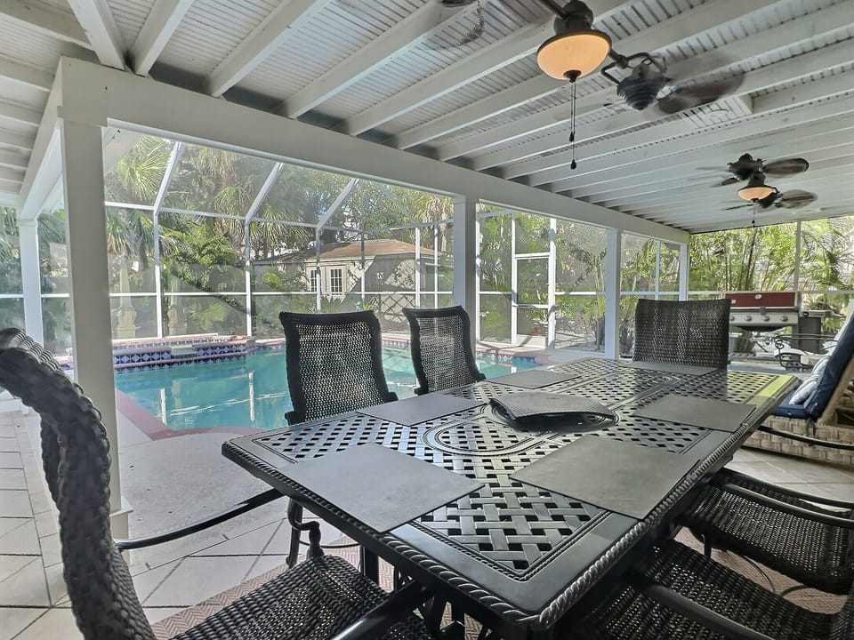 Screened pool enclosure with patio lounge chairs and tropical surrounding trees