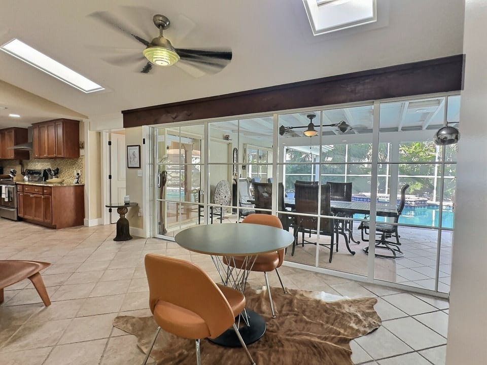 Open plan kitchen and living area with ceiling fan and sliding glass doors to pool