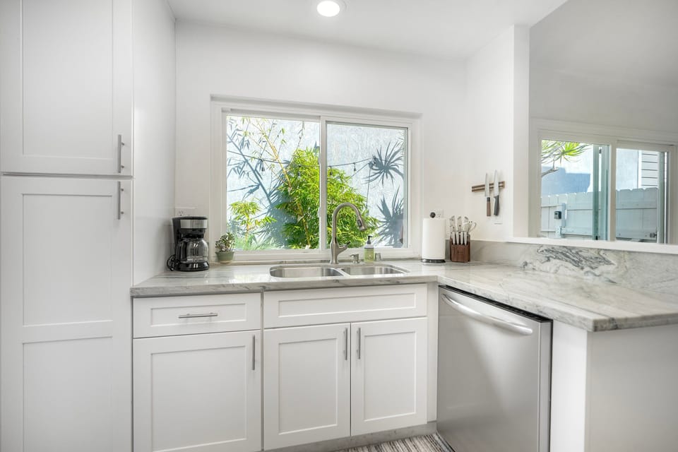 Sunlit kitchen window overlooking tropical greenery