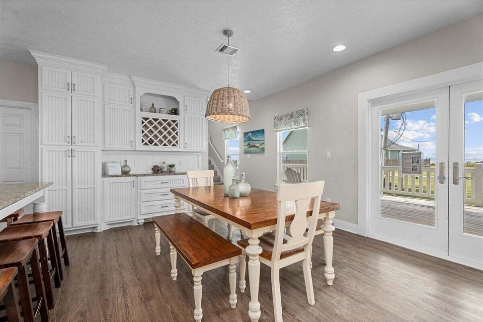 Dining space with seating for multiple guests and direct access to outdoor deck with beach views.