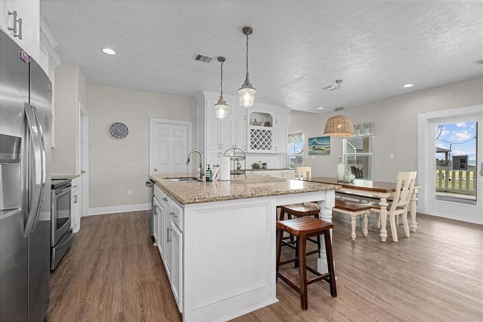 Fully equipped kitchen with large island, bar seating, stainless appliances, and modern finishes.