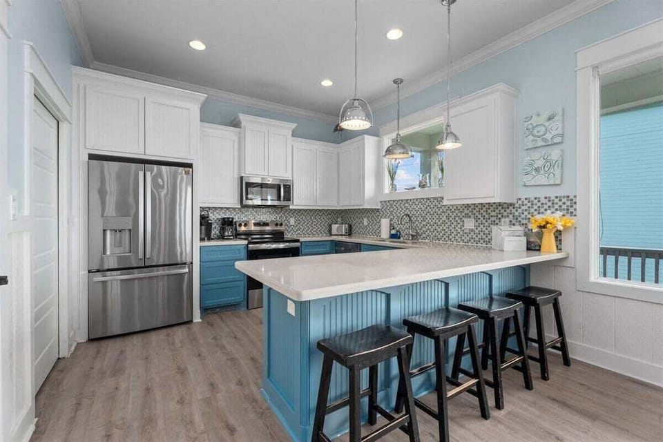 Bright kitchen featuring stainless steel appliances, large island, and bar seating—ideal for cooking during your Crystal Beach vacation.