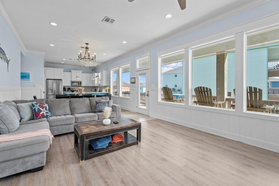 Large open living room with sectional sofa and panoramic windows offering natural light and coastal charm.