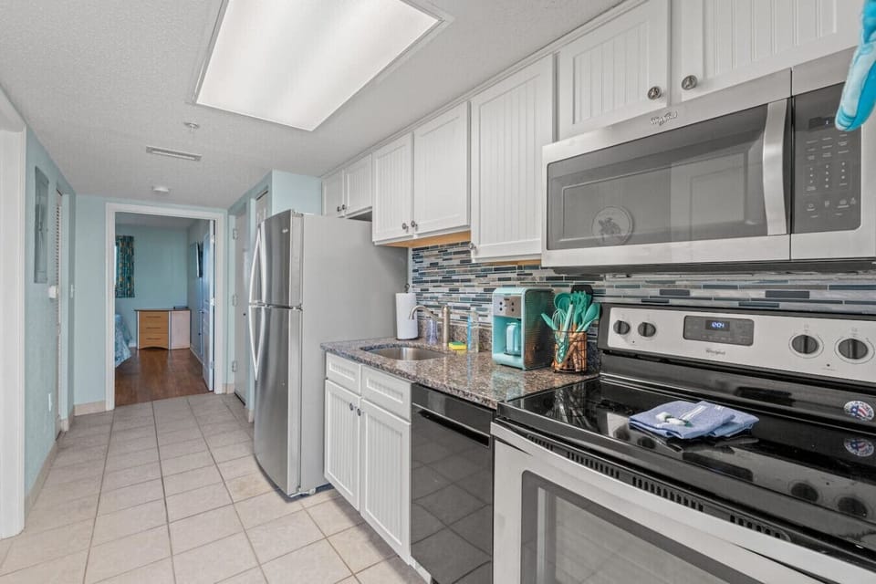 Cook your favorite meals in this fully equipped Bay Watch Resort kitchen featuring a full-size fridge, stove, oven, microwave, dishwasher, drip coffee maker, and all cooking essentials;  perfect for family vacations or extended Myrtle Beach stays.