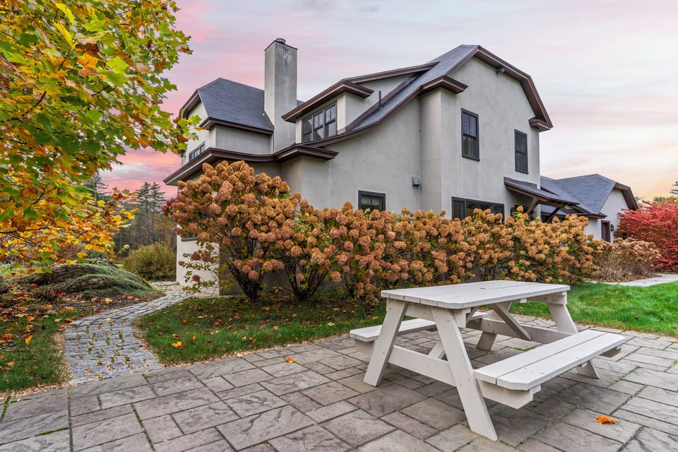 Exterior of home with stone patio and picnic table.
