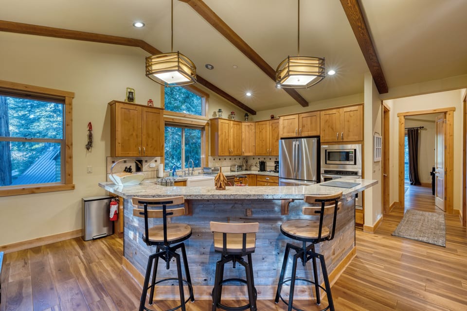 Modern kitchen with barstool seating and stainless steel appliances.