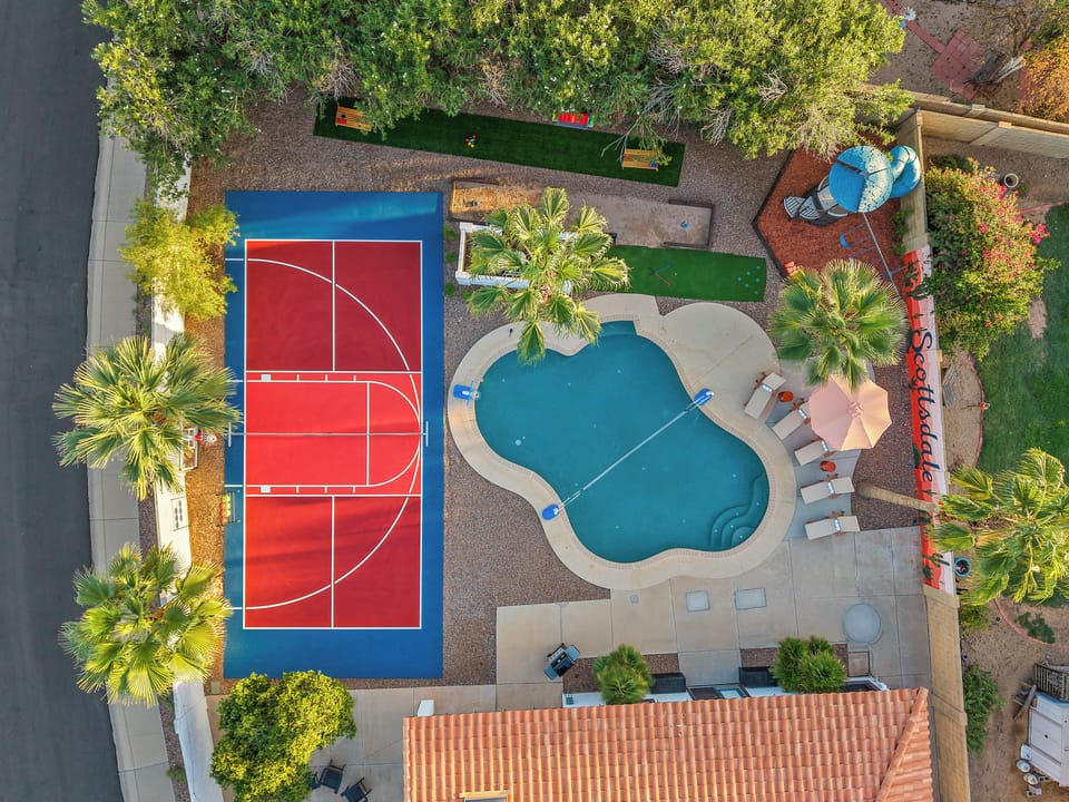 Aerial view of pool, Sports Court, and Putt Putt surrounded by lush palms.