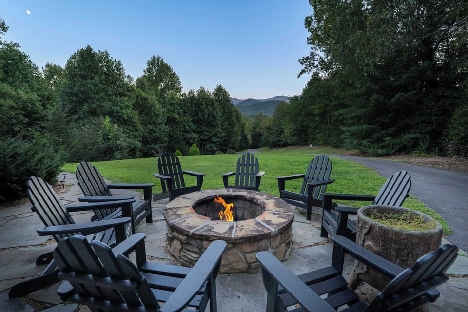 Cozy stone fire pit surrounded by Adirondack chairs with mountain views.