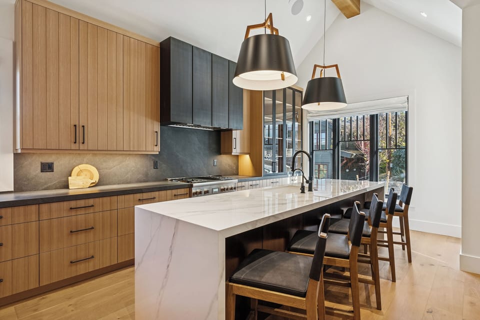 Gourmet kitchen with light wood cabinetry, marble island, and pendant lighting.