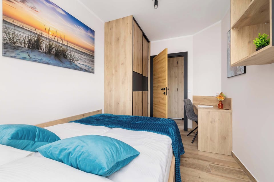 Another view of a bedroom with a blue bed, a light wood headboard, and contemporary wall art.