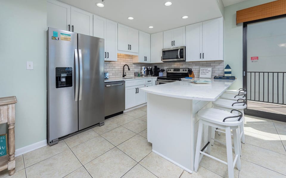 Kitchen features sleek cabinetry, modern appliances, and a breakfast bar with seating, creating a welcoming atmosphere