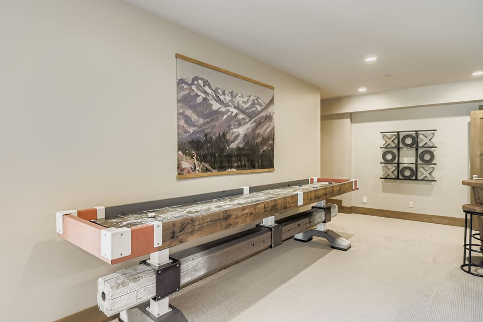 Unwind in the lower level family room with a fun shuffleboard table. The convenient wet bar has a mini-fridge and sink for snacks and drinks. Perfect for entertainment.