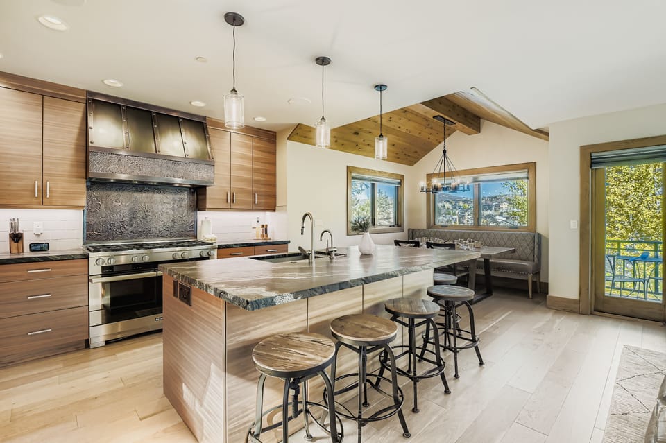 Prepare meals in our fully equipped kitchen, featuring a large island with a sink, modern stainless steel appliances, and a stylish wood-paneled design. All the essentials for a great stay.