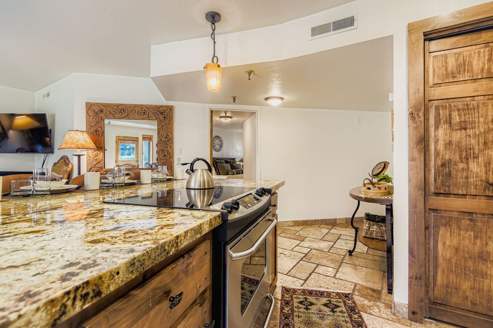 A fully equipped kitchenette with rustic wood cabinetry, granite countertops, and stainless steel appliances.