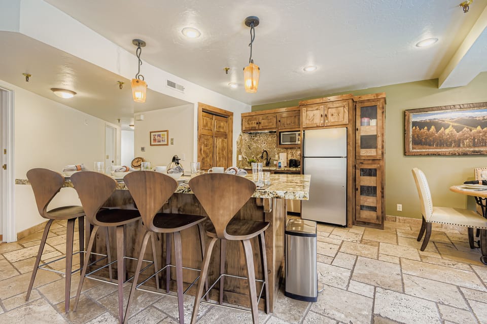 A fully equipped kitchenette with rustic wood cabinetry, granite countertops, and stainless steel appliances.