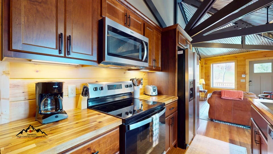 Compact yet beautifully updated kitchen featuring modern appliances, butcher block countertops, and a breakfast bar island perfect for coffee, snacks, or preparing meals after a day on the mountain.