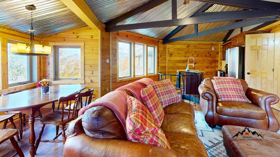 Cozy mountain living room with comfortable seating, warm rustic-modern charm, and easy access to the deck overlooking Sugar Mountain slopes and year-round mountain scenery.