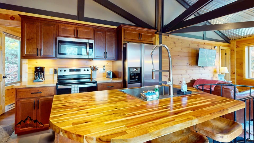 Compact yet beautifully updated kitchen featuring modern appliances, butcher block countertops, and a breakfast bar island perfect for coffee, snacks, or preparing meals after a day on the mountain.