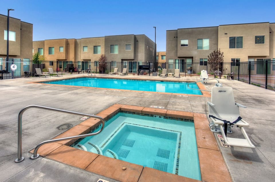 Poolside seating and shaded pergola area offering a comfortable place to unwind, gather with friends, or enjoy the warm desert sunshine.