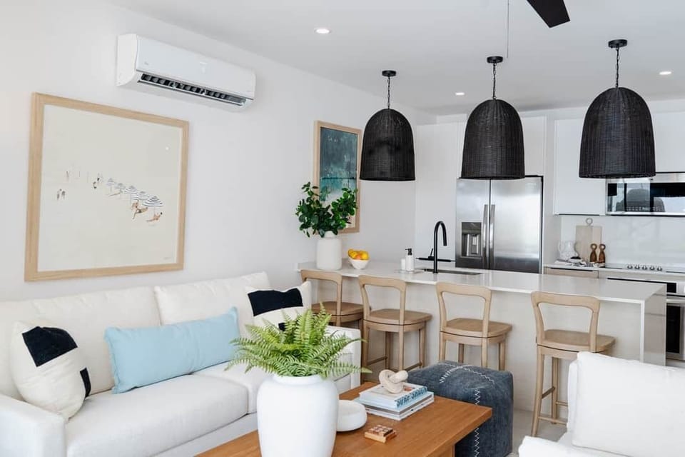 Bright open-plan lounge and kitchen with island seating, cozy sofas, and seamless indoor-outdoor flo