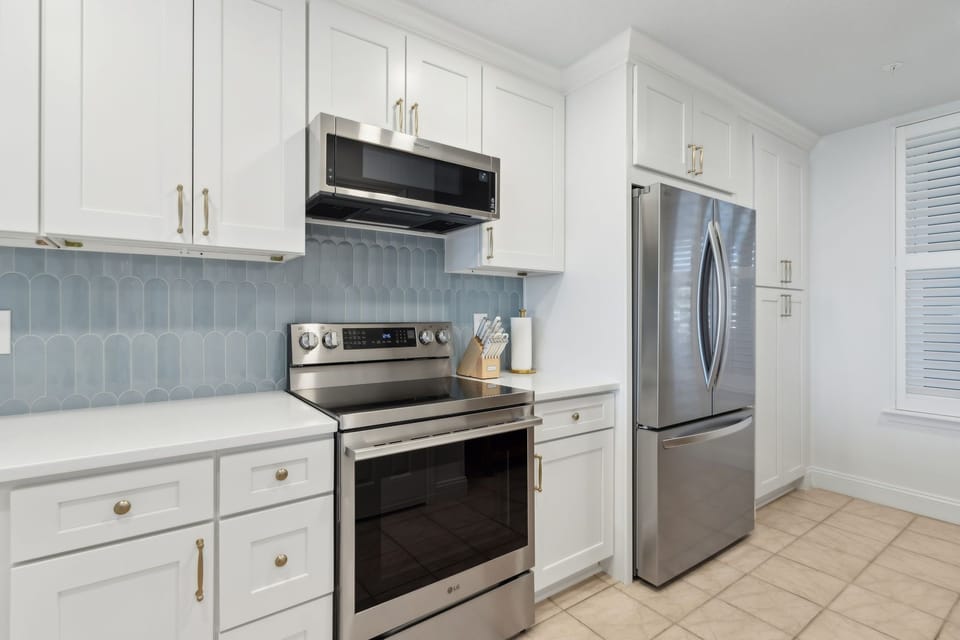 Luxury Completely Remodeled Kitchen with Stainless Steel Appliances, Stunning White Cabinetry, Quartz Countertops, a Shiplapped Island, and a Trendy Backsplash