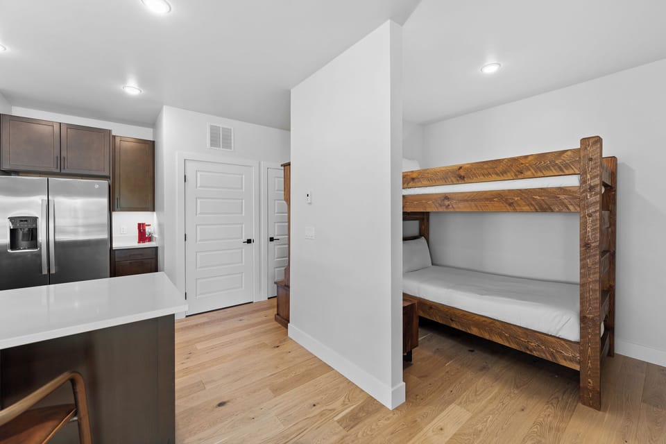 Your modern space features rustic wooden bunk beds and a sleek kitchen with stainless steel appliances, perfect for family stays.