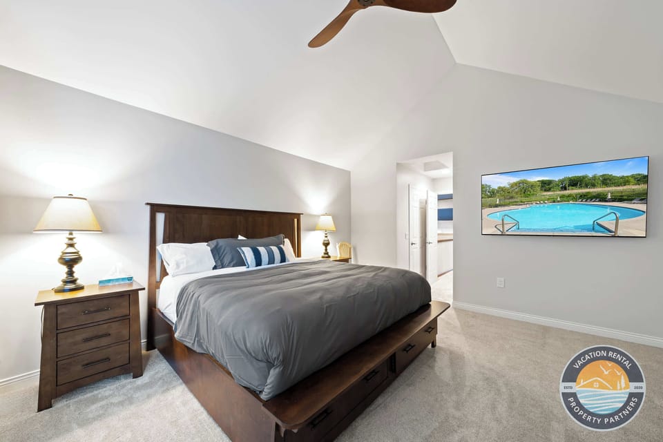 Spacious master suite with plush king bed, elegant decor, lake-themed artwork, and premium bedding. Serene atmosphere with ensuite bathroom access featuring luxurious heated floors