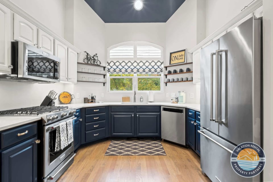 Gourmet chef's kitchen featuring dark navy custom cabinetry, quartz countertops, stainless steel appliances, and a spacious island. Modern design with all amenities for preparing memorable meals