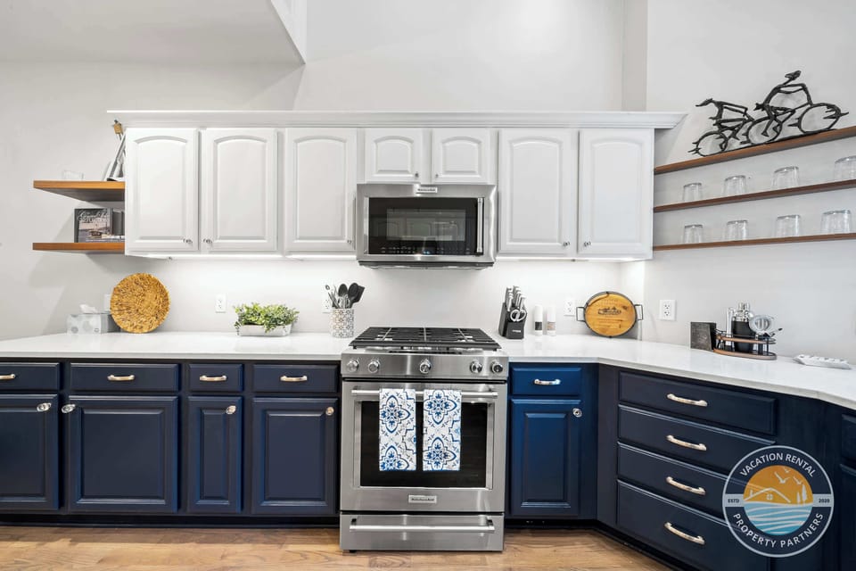 Gourmet chef's kitchen featuring dark navy custom cabinetry, quartz countertops, stainless steel appliances, and a spacious island. Modern design with all amenities for preparing memorable meals