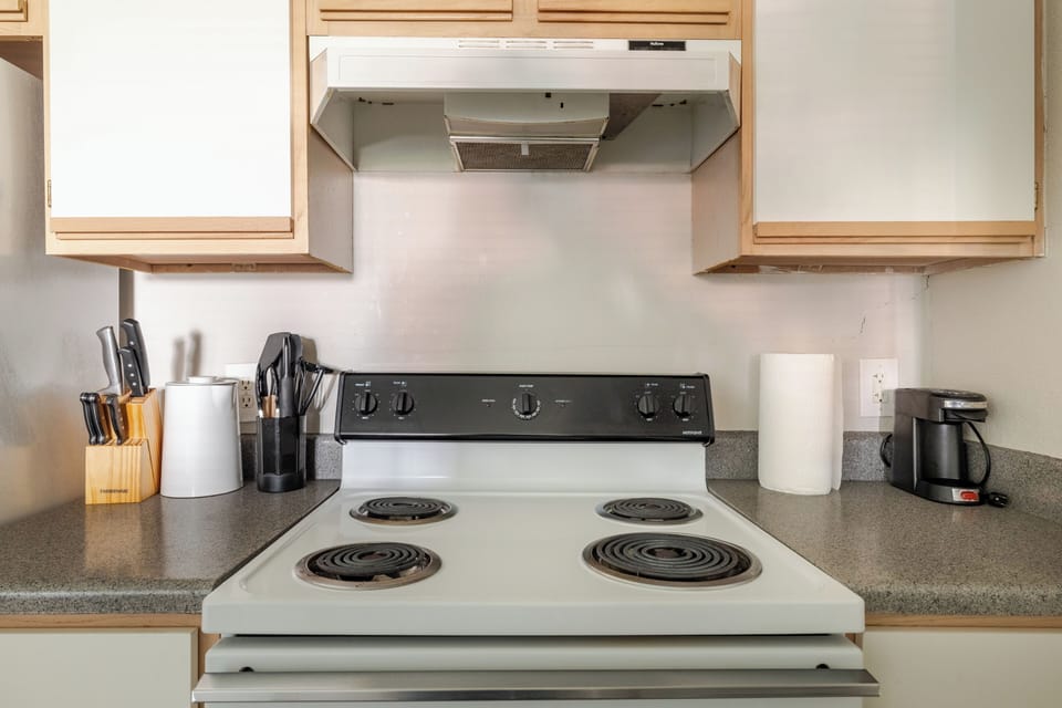 Clean, guest-ready kitchen with full stove, vent hood, and coffee maker