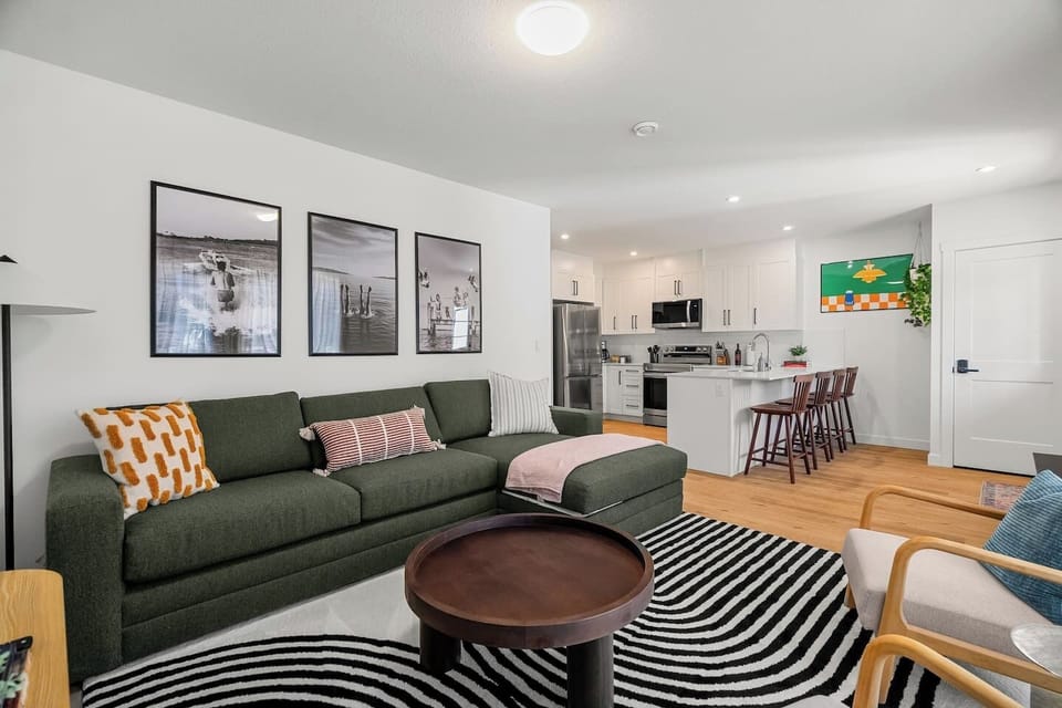 Living room with a smart TV, cozy seating options and a queen-sized pull-out sleeper sofa (all bedding provided.)