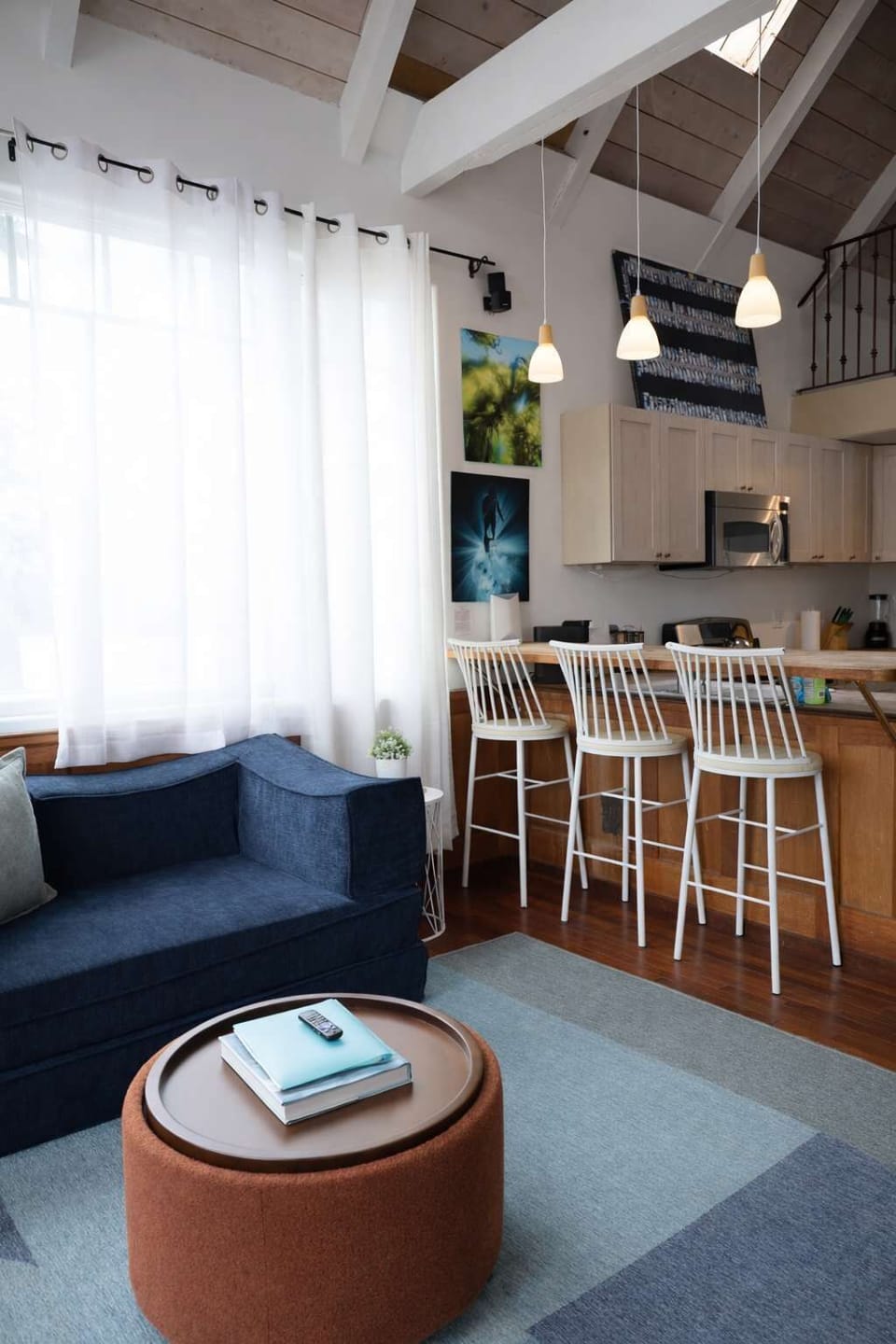 A cozy living room with soft lighting and a plush sofa flows into an open kitchen with warm tones and a small breakfast bar.