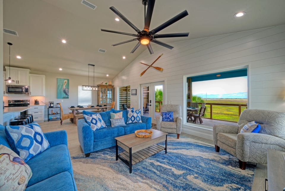 Living room with a ceiling fan, sofa, and access to the deck.