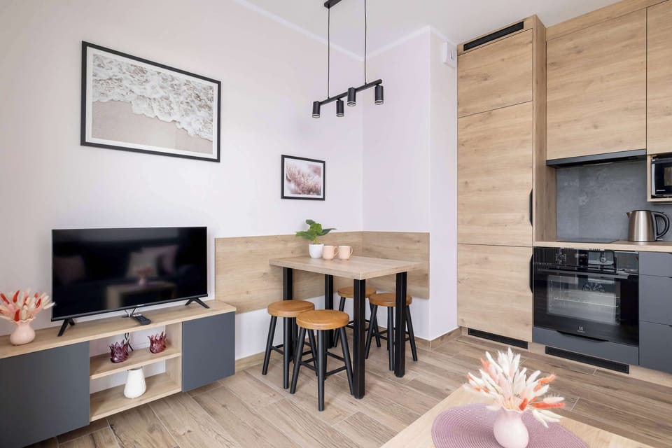 A modern kitchen area with dark cabinetry, a wooden counter, and integrated appliances, along with a small dining table.