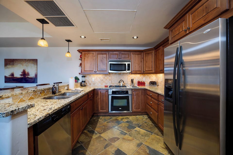 Your fully equipped gourmet kitchen features granite countertops, stainless steel appliances, and warm wood cabinetry—perfect for preparing memorable meals.
