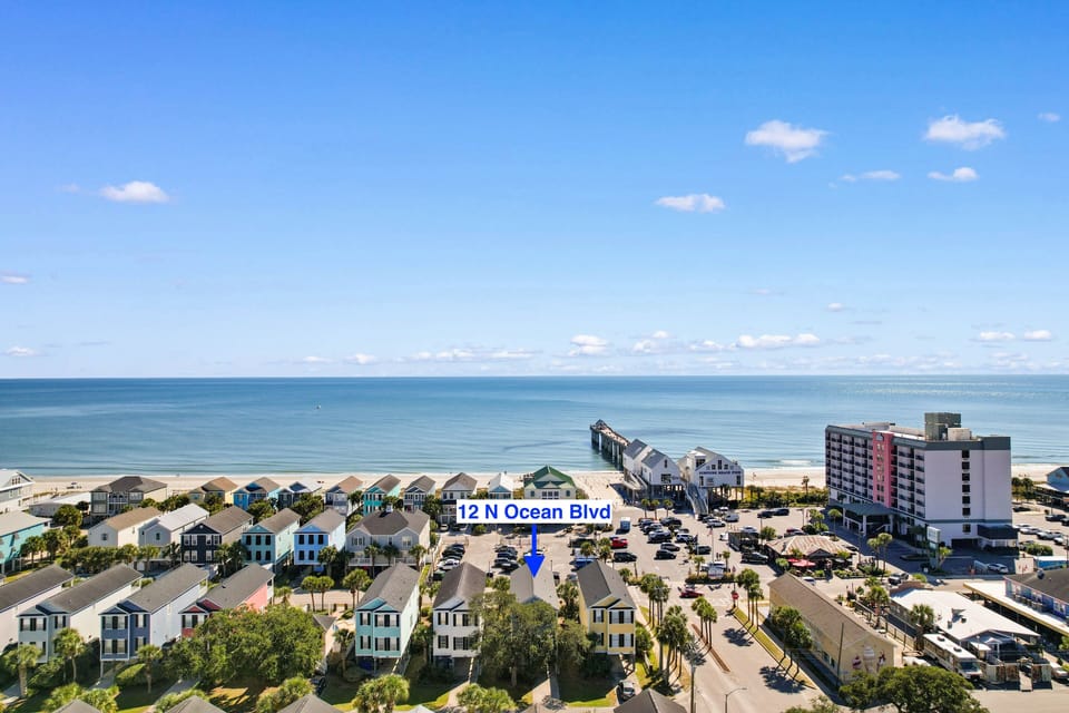 Aerial view of beachfront location with pier and colorful coastal homes marking the property address on Ocean Boulevard.