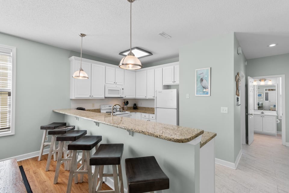 Your spacious kitchen features granite countertops, modern appliances, and a breakfast bar perfect for morning coffee or casual meals together.