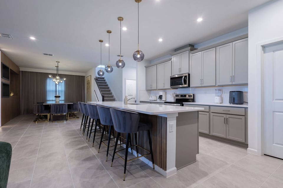Step into a stylish kitchen featuring sleek gray cabinetry and a generous island with chic pendant lighting. The open layout seamlessly connects to a dining area, inviting you to gather and indulge in culinary delights.
