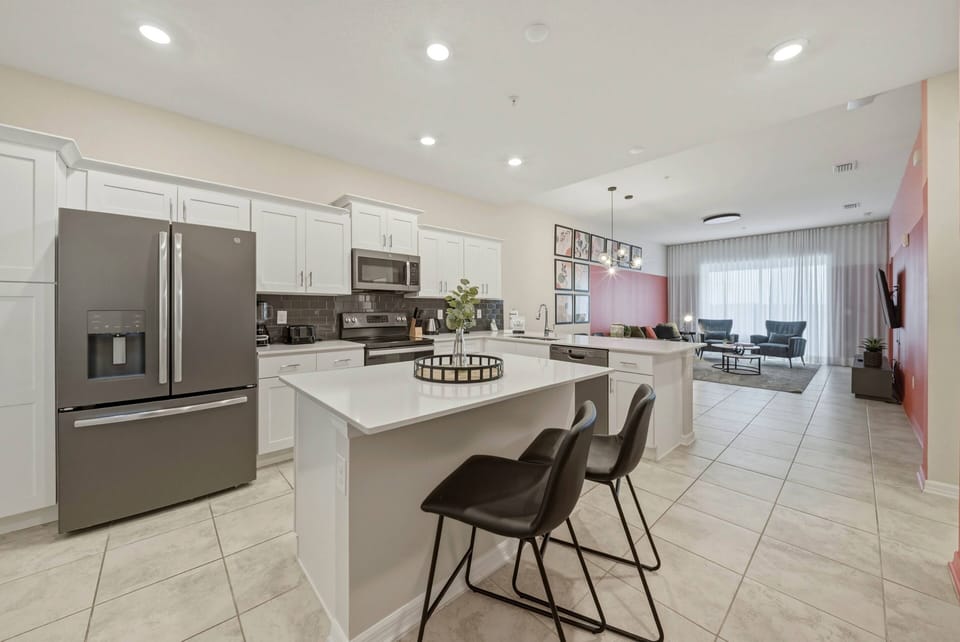 Welcome to this modern kitchen featuring sleek white cabinets and dark appliances. The spacious island with stylish black stools is perfect for casual dining, while large windows bathe the area in natural light for a warm.