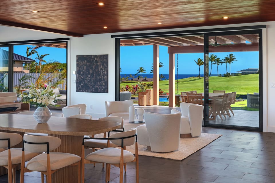 Dining area framed by warm wood ceilings and panoramic island views, offering an inviting setting for shared meals.