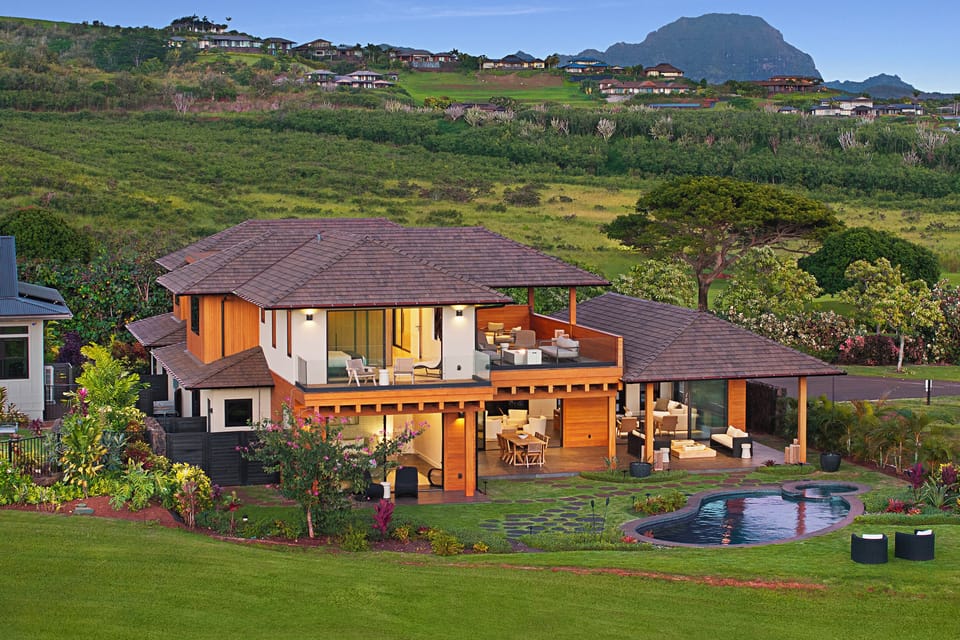 Modern luxury estate with private pool nestled in lush tropical landscaping and a scenic mountain backdrop.