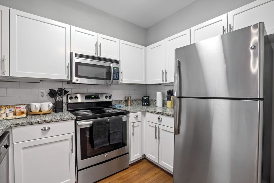 Another view — stainless fridge, stove, microwave & granite counters throughout