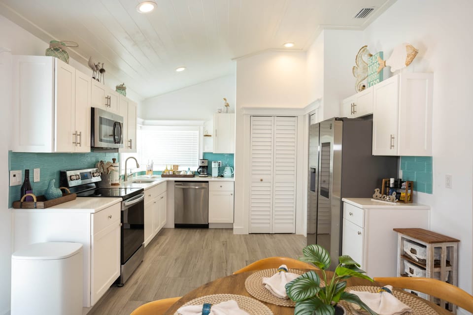 Open coastal kitchen with stainless appliances and a stunning sea-glass backsplash.