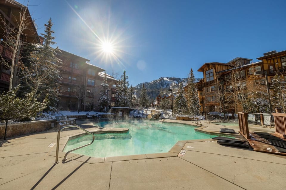 Club Solitude: Outdoor heated pool with mountain backdrop and sunny deck area.