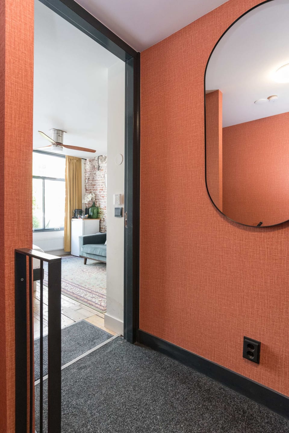 Bold terracotta-toned hallway with curved mirror detail sets the tone for a stylish and welcoming stay.